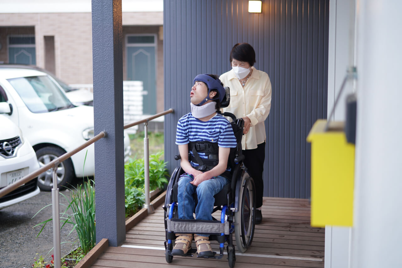 玄関スロープにて車椅子の利用者様とスタッフの様子