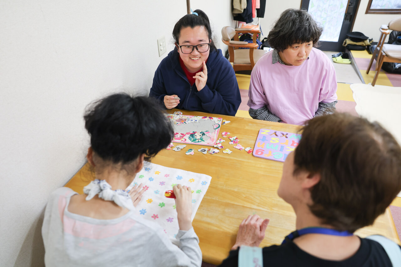 テーブルで重い思いの活動をする利用者様たちとサポートするスタッフの様子