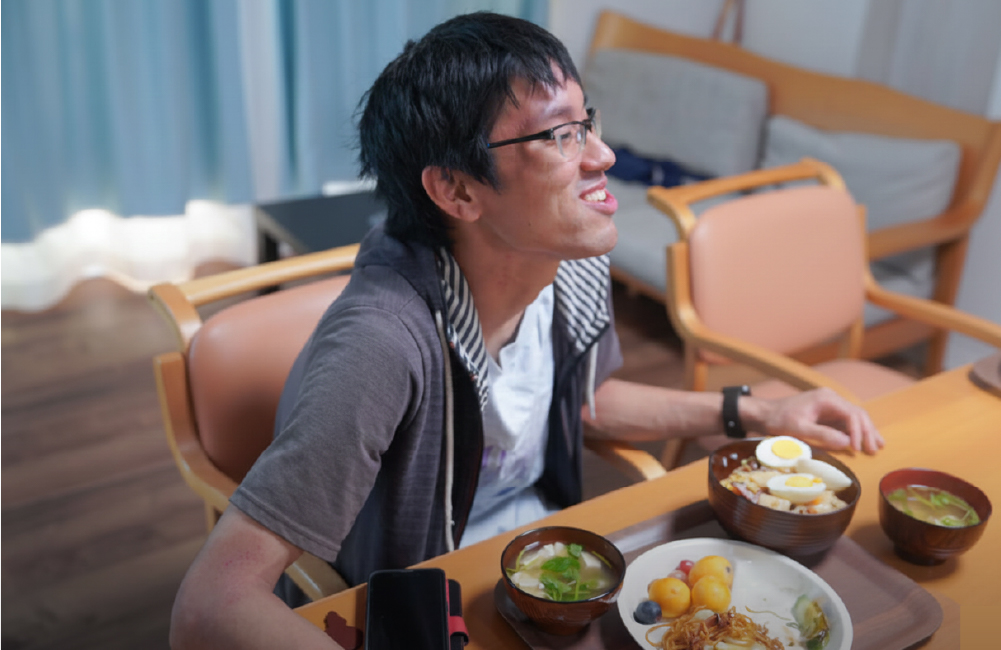 グループホームの食卓で笑顔でご飯を食べる利用者さん